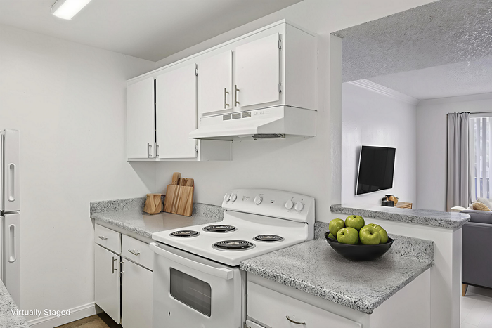 Bright, modern kitchen with sleek white cabinets, granite countertops, and an inviting open layout overlooking a cozy living room.