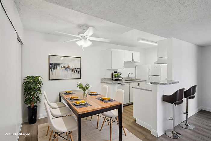 Chic and modern dining area with elegant artwork, sleek white cabinets, and a cozy breakfast bar with high stools.