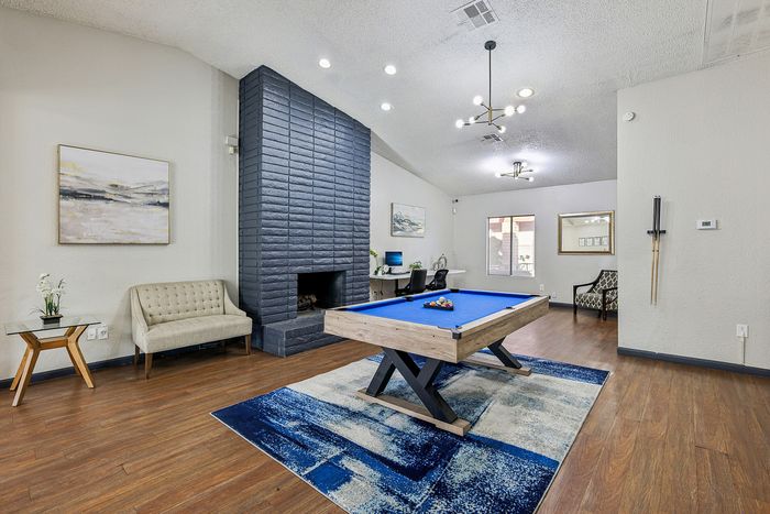 Chic recreational room with a modern pool table, elegant fireplace, and cozy seating area, ideal for entertainment and relaxation.
