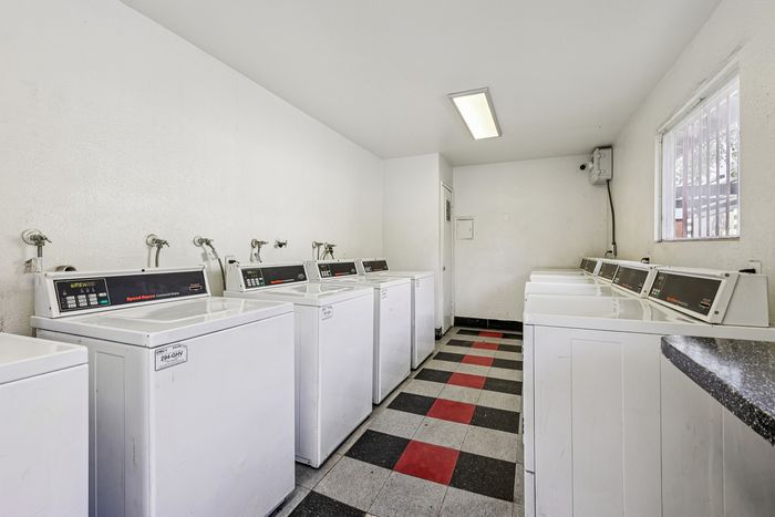 Modern laundry room equipped with multiple washers, featuring a sleek black and red checkered floor design.