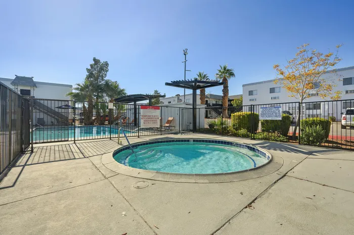 Inviting outdoor area featuring a sparkling pool and relaxing spa, surrounded by palm trees and lush greenery, perfect for unwinding in the sun.