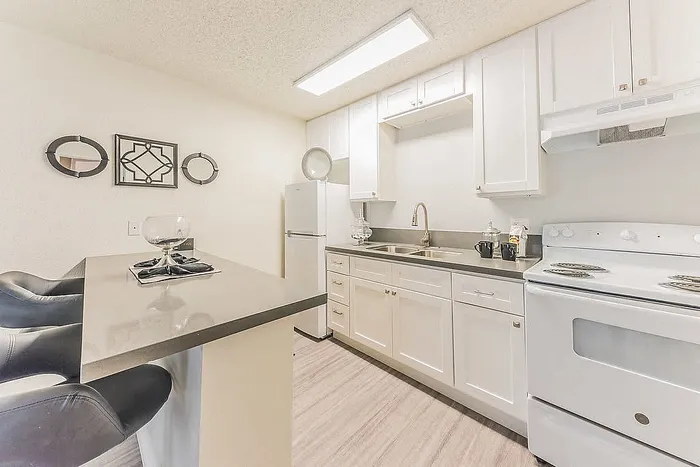 Modern kitchen with sleek white cabinetry, stainless steel sink, and cozy breakfast bar for casual dining.
