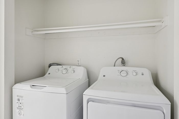 Contemporary laundry setup featuring a sleek washer and dryer with ample overhead shelving for convenience.