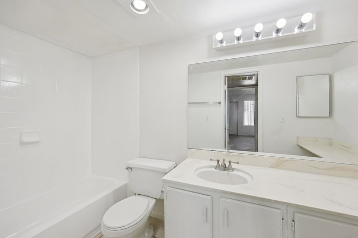 Bright and modern bathroom featuring a sleek vanity mirror, elegant countertop, and inviting bathtub, exuding a fresh and clean ambiance.