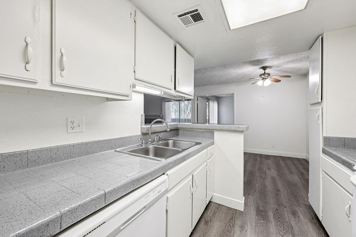 Bright and inviting kitchen with sleek white cabinetry, modern countertops, and an open view to the dining area, enhanced by natural light.
