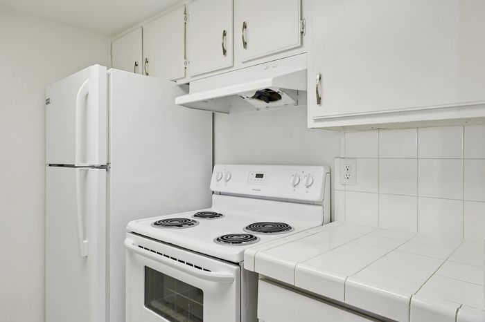 Bright and inviting kitchen featuring modern appliances, sleek cabinetry, and clean tile countertops, perfect for culinary creativity.