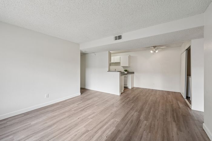 Spacious and modern open-plan living area with elegant wooden flooring and a sleek, minimalist kitchen design.