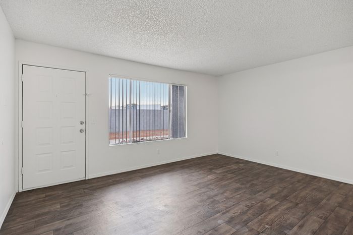 Bright and inviting empty room with elegant wood flooring and large window, perfect for customizable living space.
