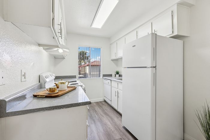 Bright, modern kitchen with sleek countertops, white cabinetry, and natural light streaming through a window.