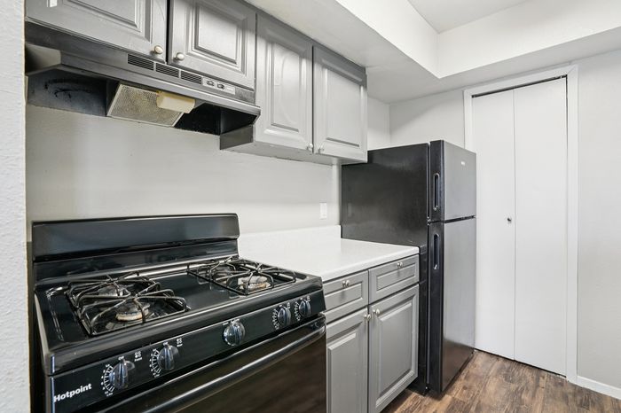 Modern kitchen featuring sleek black appliances, elegant gray cabinetry, and polished white countertops for a stylish cooking space.