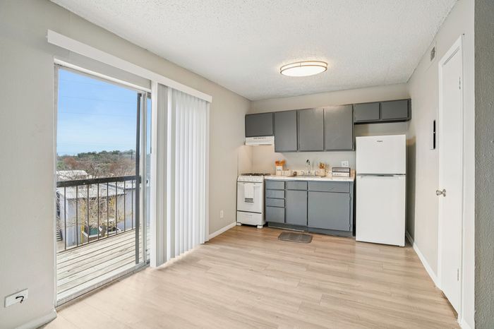 Modern kitchen with sleek gray cabinetry, natural light from a large balcony window, perfect blend of style and functionality.