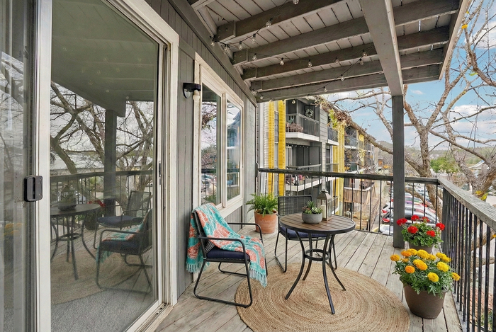 Charming apartment balcony with cozy seating, colorful potted flowers, and a serene view, ideal for relaxation and outdoor enjoyment.