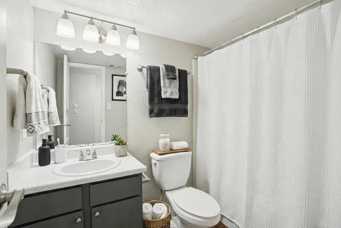 Modern bathroom with elegant fixtures, large mirror, and neutral decor featuring plush towels and chic accessories.