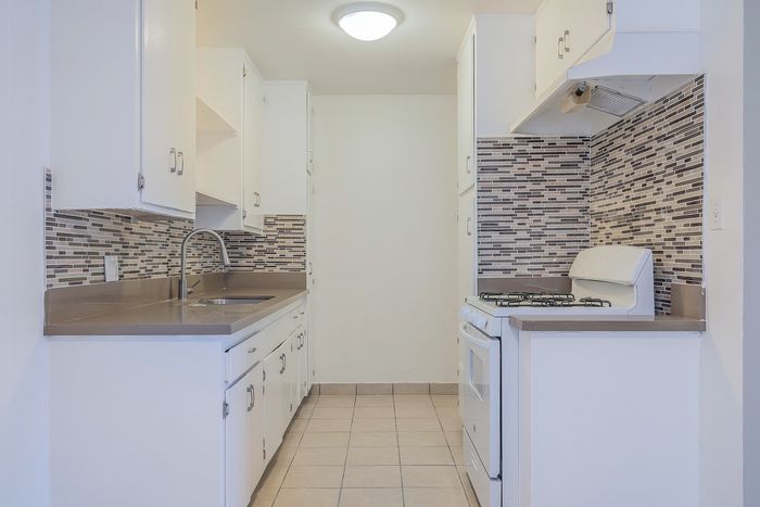 Bright and modern kitchen with sleek countertops, stylish backsplash tiles, and ample cabinetry for a chic, functional space.