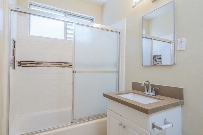 Bright, modern bathroom featuring sleek shower doors, elegant tile accents, and a stylish vanity with ample light.