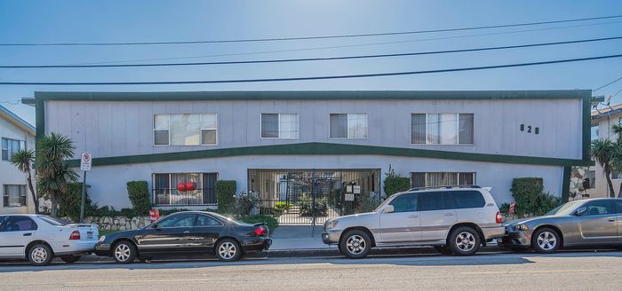 Charming apartment complex with modern design, lush greenery, and convenient street parking, perfect for comfortable urban living.