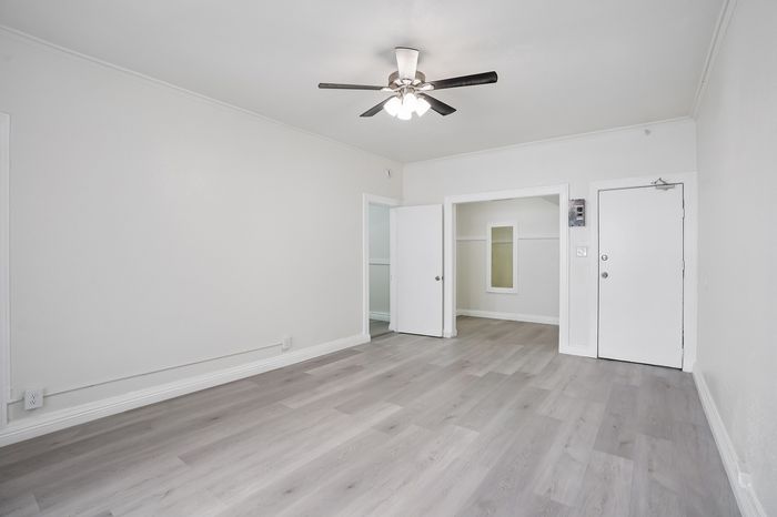 Bright, open space with sleek hardwood floors and ceiling fan, perfect for a modern living room setup.