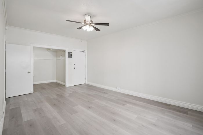 Bright and inviting living room with modern ceiling fan and elegant light wood flooring.