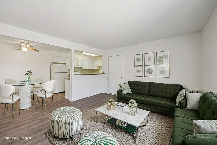Chic and modern open-plan living room with plush green sofas, stylish decor, and a cozy dining area adjacent to a contemporary kitchen.