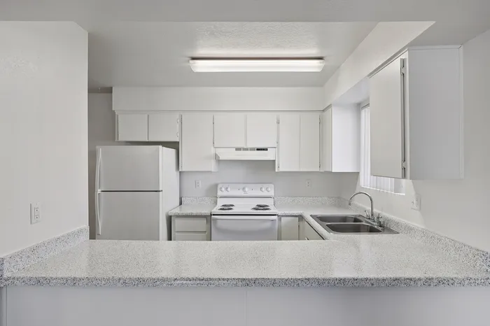 Bright and modern kitchen with sleek white cabinetry, spacious countertop, and contemporary appliances.