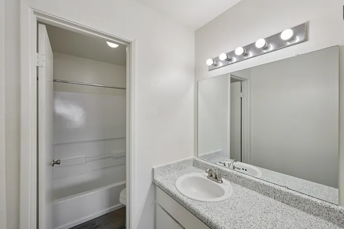 Bright, modern bathroom with sleek granite countertop, elegant lighting, and clean white fixtures.