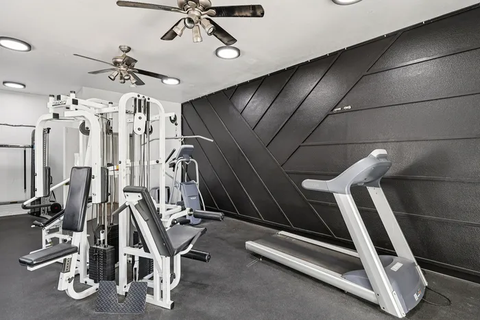 Modern fitness room with sleek black walls, high-end gym equipment, and a spacious layout for optimal workouts.