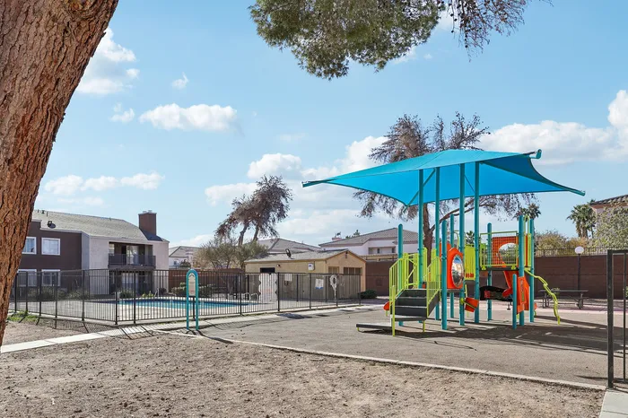 Bright and inviting apartment community playground with colorful equipment and a refreshing pool, perfect for family fun.