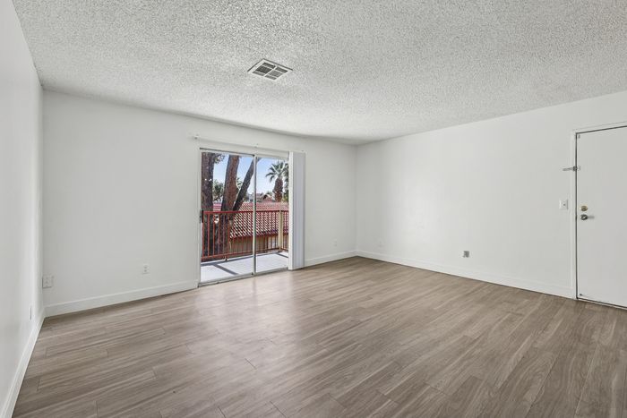 Bright and airy living space with elegant wooden floors and a charming view through glass doors leading to a balcony.