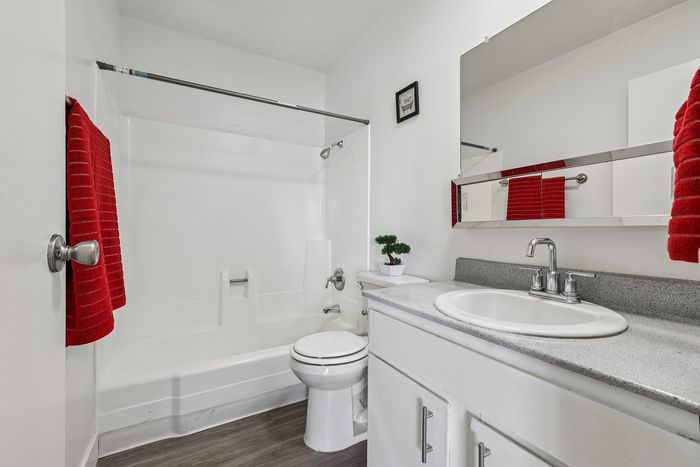Bright and modern bathroom featuring white fixtures, sleek countertop, and a touch of elegance with vibrant red towels.