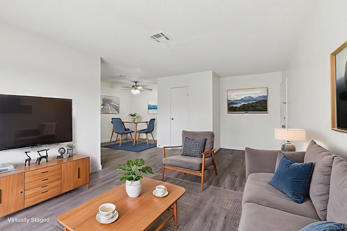Bright and modern living area with sleek furnishings, large TV, and stylish decor, leading to a chic dining space perfect for entertaining.