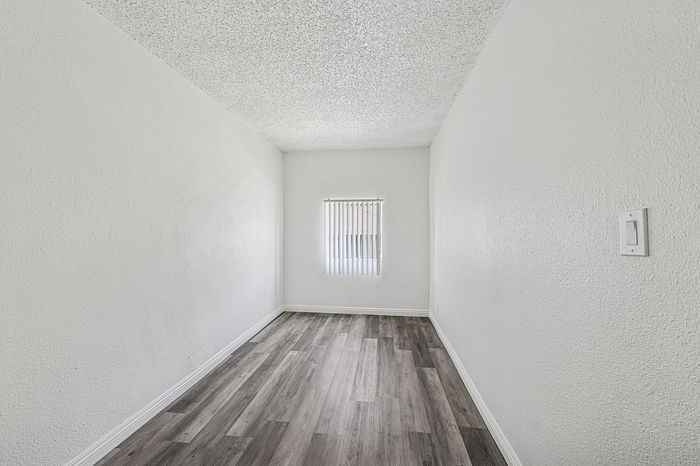 Bright, minimalist room with modern wood flooring and a large window perfect for natural light.