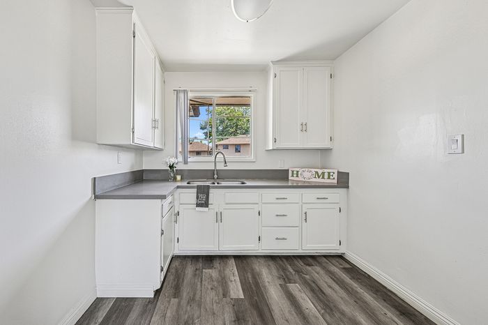Charming, bright kitchen with modern white cabinetry, sleek gray countertops, and a cozy window view.