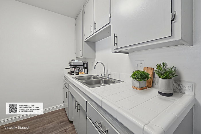 Sleek kitchen featuring modern white cabinetry, dual sink, and spacious countertop with fresh herb accents.