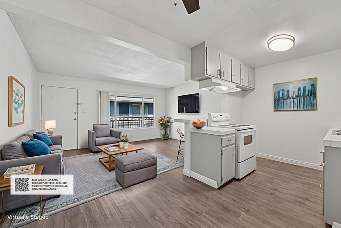 Contemporary open-plan living room and kitchen with cozy seating area, bright windows, and sleek modern decor.