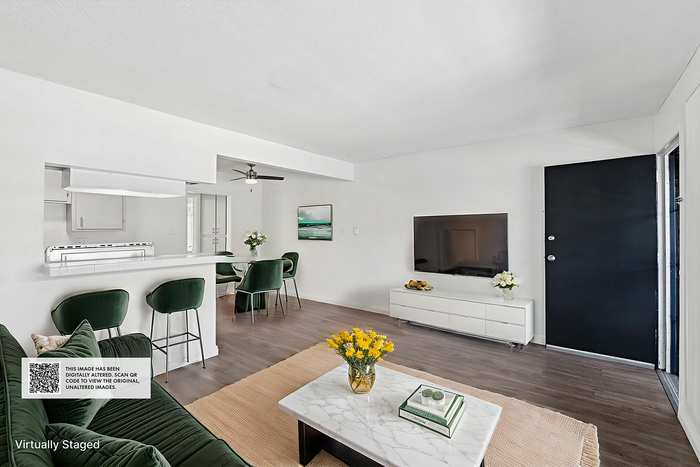 Chic and modern living space with stylish green velvet seating, sleek white cabinetry, and an inviting open-concept layout.