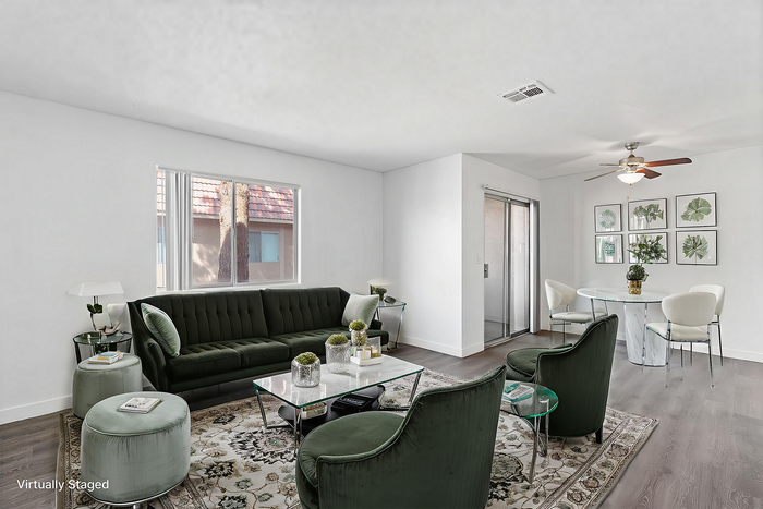 Elegant living room with plush green velvet seating, stylish glass coffee table, and modern dining area, showcasing a serene and inviting ambiance.