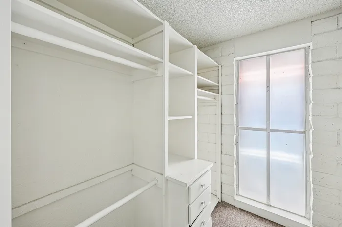 Bright walk-in closet with ample shelving and natural light, perfect for organized living.