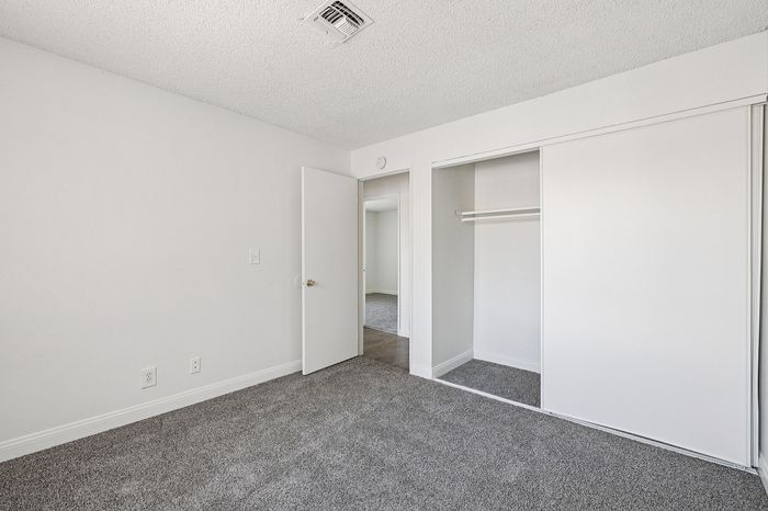 Bright and airy bedroom with plush carpeting, featuring a spacious closet and modern white walls.