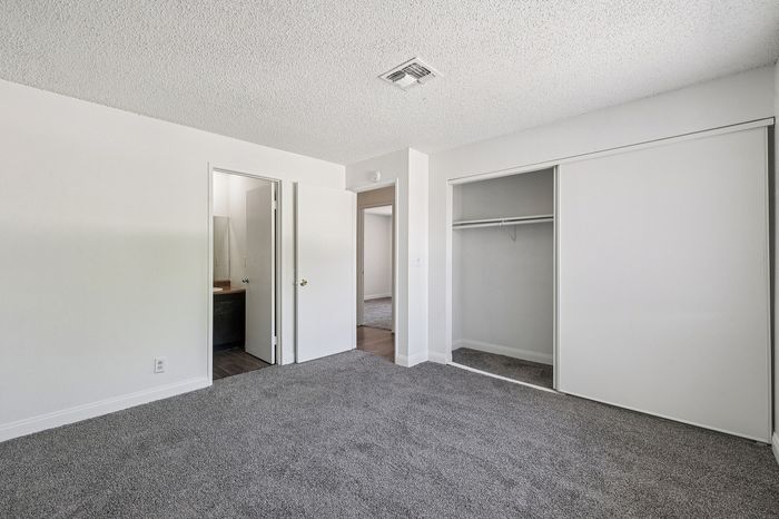 Bright and spacious bedroom with plush carpeting, large closet, and en-suite bathroom for modern living.