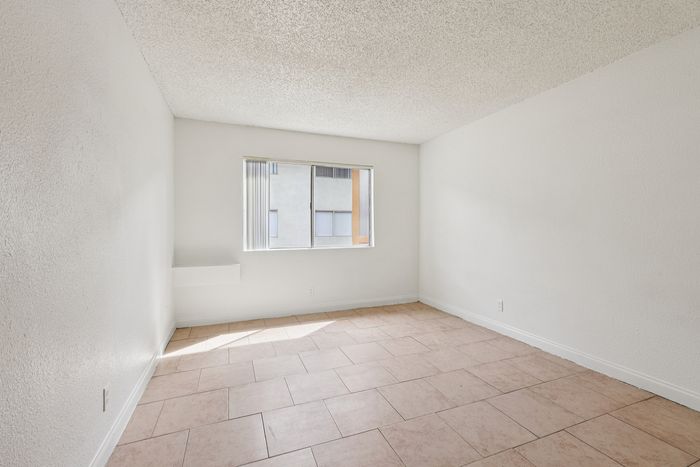 Bright minimalist room with textured ceilings and large window, ideal for a serene living space.