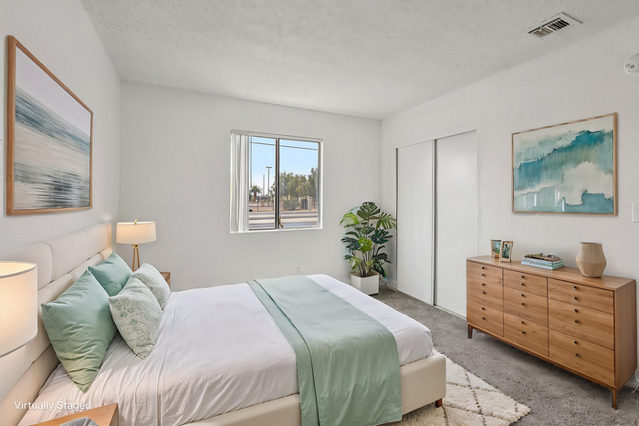 Bright and inviting bedroom with modern decor, featuring a comfortable bed, stylish artwork, and a touch of greenery for a relaxing atmosphere.