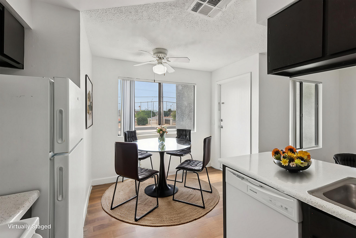 Bright and modern kitchen with a cozy dining area, featuring a round table with four sleek chairs, large windows enhancing light, and elegant floral d&eacute;cor.
