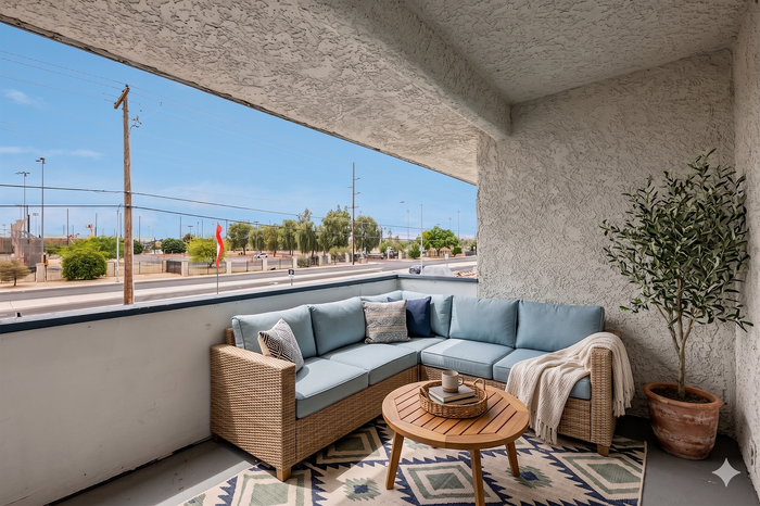 Charming outdoor balcony with cozy wicker seating, soft blue cushions, and a stylish coffee table, offering a relaxing spot with scenic views.
