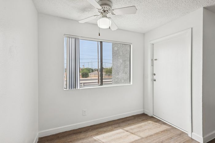 Bright room with a sleek ceiling fan, large window offering a scenic view, and chic wood flooring.
