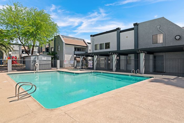 Inviting apartment complex with a sparkling outdoor pool surrounded by vibrant landscaping and modern architecture.