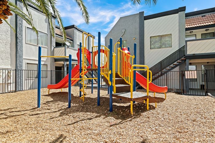 Vibrant playground with colorful slides and climbing structures, nestled in a charming apartment community.