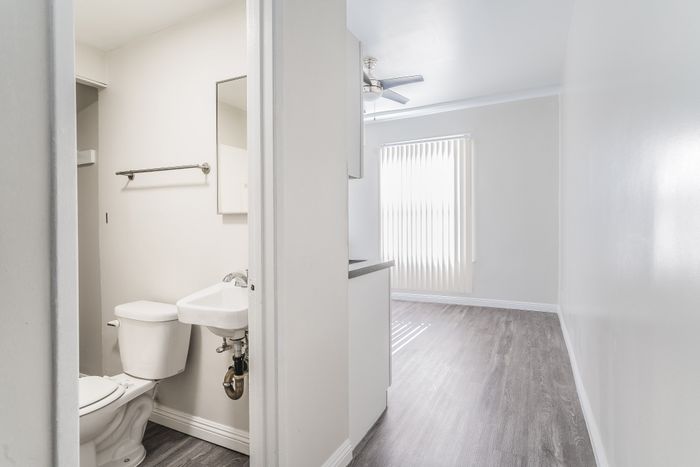 Modern apartment interior with a sleek bathroom and sunlit room featuring elegant vinyl plank flooring and contemporary design.