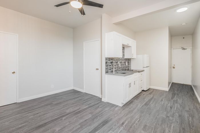 Modern apartment interior featuring sleek grey flooring, elegant white cabinetry, and a stylish kitchen with mosaic backsplash for an inviting atmosphere.