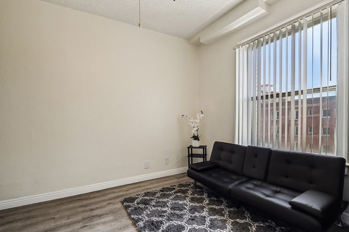 Cozy living space with plush black sofa, elegant floral decor, and large window offering ample natural light.