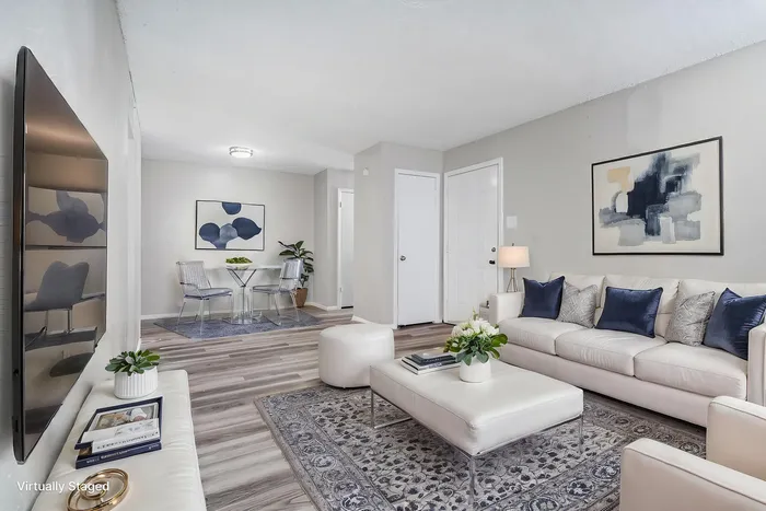 Inviting living room with elegant white sofa, chic abstract art, and modern glass dining table, perfect for effortless entertaining.